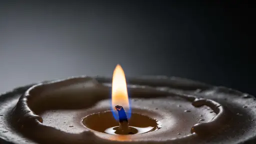 Single candle flame captured as a low-key fine-art photograph in total darkness, composed and cropped for a 16:9 wallpaper or poster with serene mood and rich warm tones.