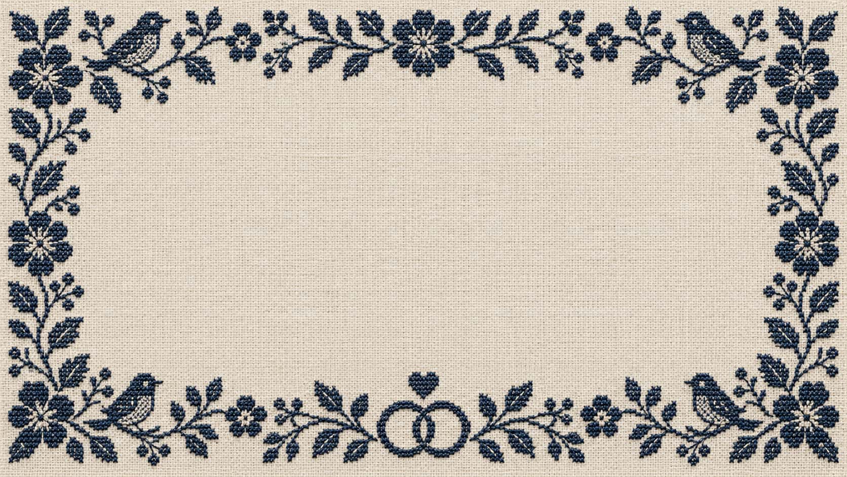 A wide light linen card background with a dark navy counted-stitch border of flowers, leaves and small birds along the four edges, two interlocking rings and a small heart at the bottom centre and a large plain linen middle.