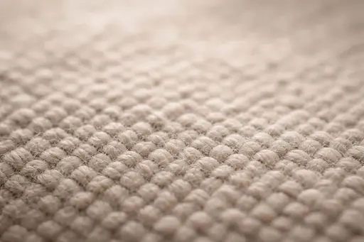 Extreme close-up macro photograph of soft woven fabric showing interlaced threads, tactile fiber texture, subtle specular highlights, and shallow depth for a background image.