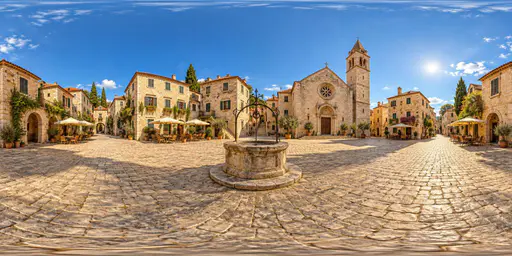 A full 360 degree equirectangular panorama from the centre of a historic stone town square with cobbled paving, a well, old townhouses with shuttered windows, a church tower and cafe tables with umbrellas.