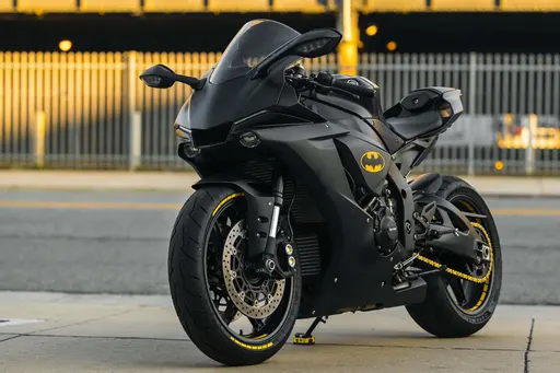 A matte-black sport motorcycle photographed as a low-angle product study that fills the lower two-thirds of a 3:2 poster-cover composition with dramatic rim lighting.