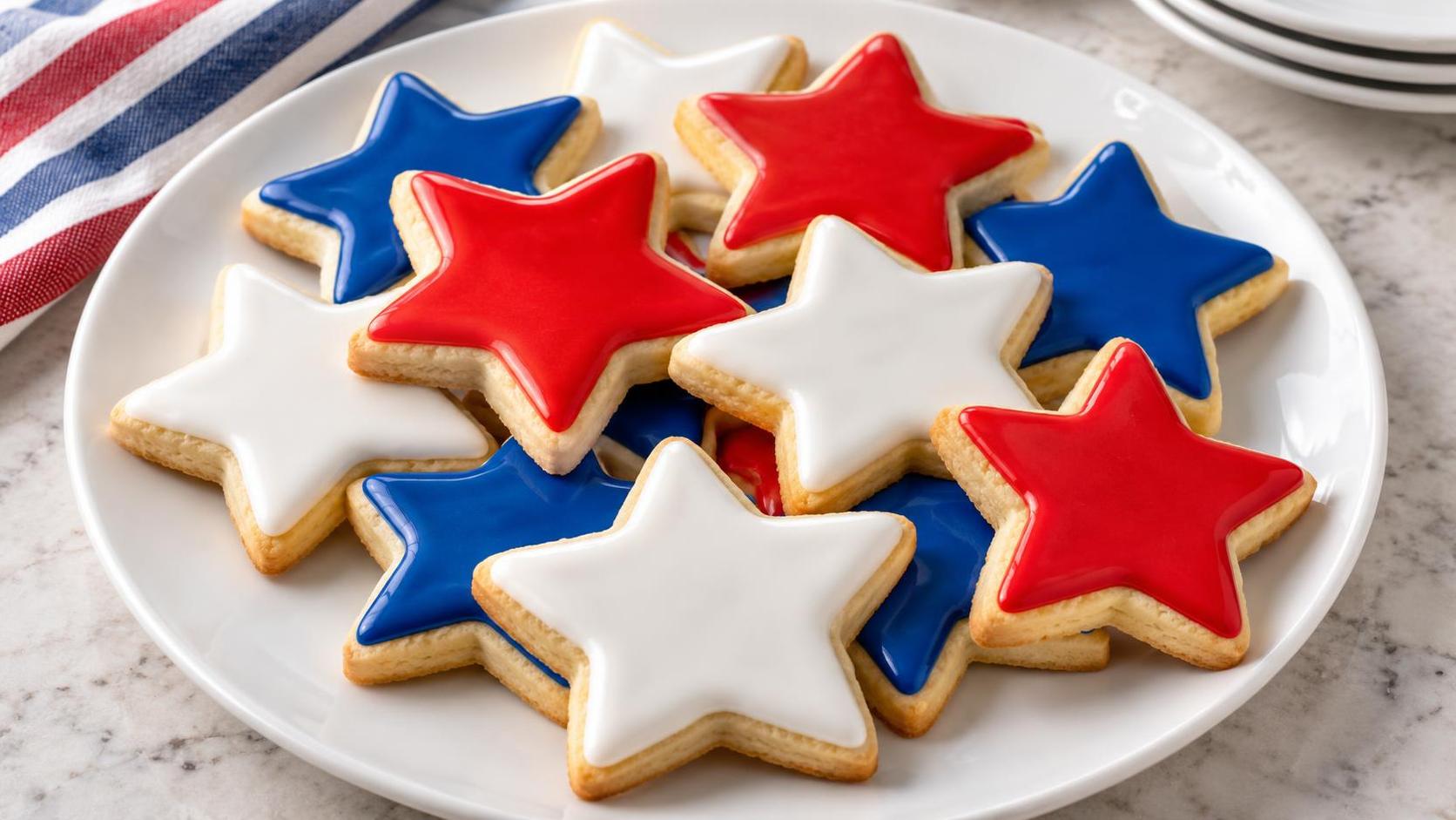 Star-shaped sugar cookies in red, white and blue on a plate.
