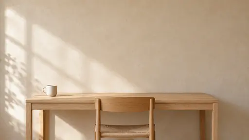 A smooth sand-coloured plaster wall with an empty upper two thirds, a plain oak desk with a woven-seat chair in front and a small white cup, window light from the left.