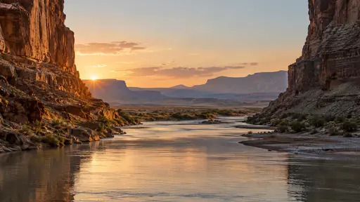 The canyon walls open out at the canyon mouth in warm evening light where the river channel runs on into a wide flat valley.