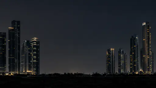 Two groups of tall dark towers with a few lit windows stand separated at night by one broad empty gap of sky and low dark ground.