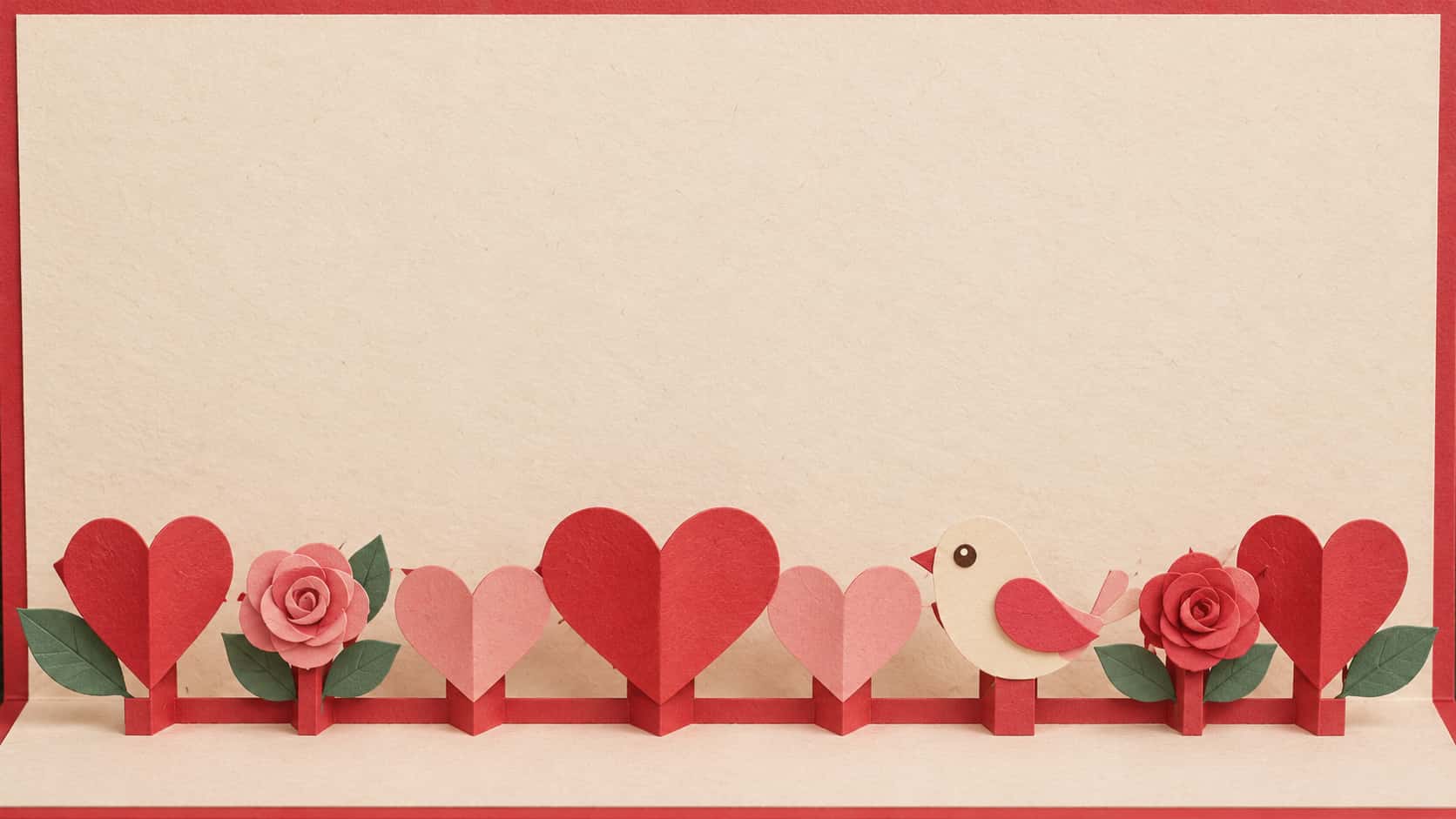 A wide cream pop-up card with a red border, paper hearts, roses and a small bird standing up from the base on folded hinges along the bottom and a large empty upper card.