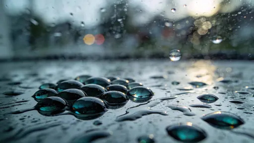 Close-up of a rain-speckled window photographed in a 16:9 crop, shallow focus on droplets with the outside scene soft and heavily blurred to abstract shapes.